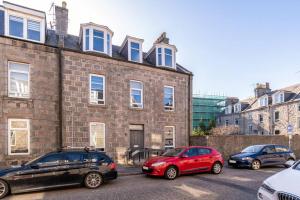 three cars parked in front of a brick building at Remodelled Luxury 3 Bed Apartment in Aberdeen