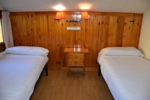 two beds in a room with a wooden wall at Apartamentos SNÖ Edelweiss in Cerler