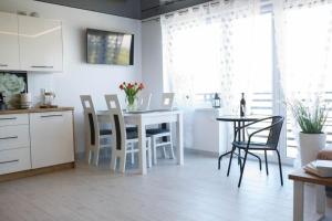 kuchnia i jadalnia ze stołem i krzesłami w obiekcie Apartamenty Scarlet w mieście Darłowo