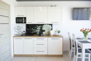 a kitchen with white cabinets and a table at Apartamenty Scarlet in Darłowo