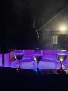 three wine glasses sitting on a table in front of a pool at Casa de Vacanta Diana Moneasa in Moneasa