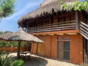 a building with a thatch roof and a table and a patio at Cabañas Las 3 Marias in San Agustinillo