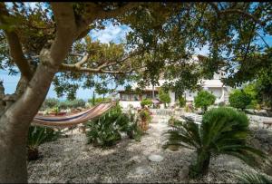 a hammock in a garden with plants and a house at La Villa del Conte in Scicli