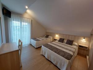 a hotel room with two beds and a desk at Mirador do faro Touriñan in Muxia