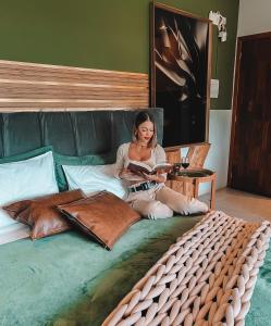 La Contemporânea Cabanas prox a cidade vista para ponto turístico في أوروبيسي: امرأة تجلس على سرير وتقرأ كتاب