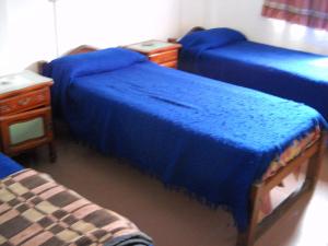 Habitación con 3 camas azules y mesa. en Hotel Aeropuerto Monte Grande en Monte Grande