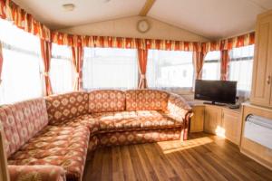 a living room with a couch and a television at 6 Berth Caravan For Hire, Minutes From A Stunning Beach In Norfolk! Ref 21036f in Heacham