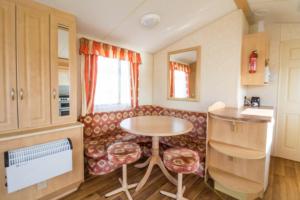 sala de estar con mesa y sofá en 6 Berth Caravan For Hire, Minutes From A Stunning Beach In Norfolk! Ref 21036f, en Heacham