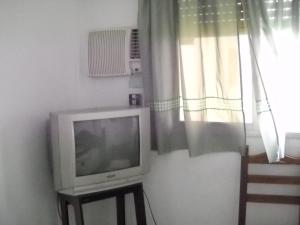 una tv seduta su un supporto accanto a una finestra di Hotel Aeropuerto Monte Grande a Monte Grande
