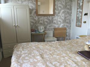a bedroom with a bed and a dresser and a cabinet at Arun Sands Rooms in Littlehampton