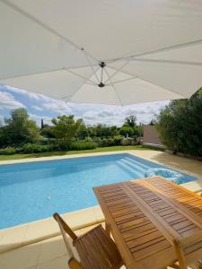 una piscina con tavolo, sedie e ombrellone di Gîte "Au Bord de l'Eau" a La Force