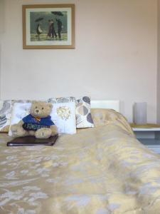 a teddy bear sitting on top of a bed at Arun Sands Rooms in Littlehampton