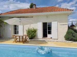 una casa con tavolo e ombrellone accanto a una piscina di Gîte "Au Bord de l'Eau" a La Force