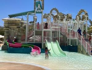 uma menina parada na água em um parque aquático em Castle beach hotel em Aqaba