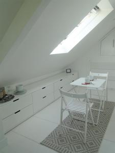 a white kitchen with a white table and chairs at Cober House in Helston