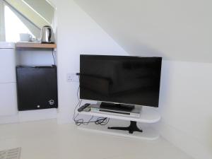 a flat screen tv sitting on a stand in a room at Private Double Room and Ensuite in Historic Cornish Cottage in Helston