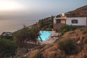a house with a swimming pool next to the ocean at Kea Boho Luxury with Pool & Stunning Views in Melissaki