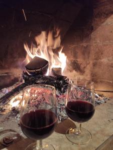two glasses of wine in front of a fire at Family Hotel Sani in Kvatsʼkhutʼi