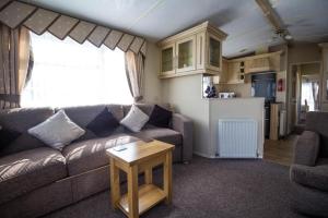 ein Wohnzimmer mit einem Sofa und einem Tisch in der Unterkunft Great 6 Berth Caravan For Hire At Cherry Tree Holiday Park In Norfolk Ref 70801c in Great Yarmouth