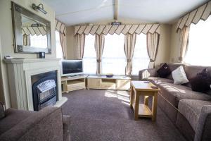 a living room with a couch and a fireplace at Great 6 Berth Caravan For Hire At Cherry Tree Holiday Park In Norfolk Ref 70801c in Great Yarmouth