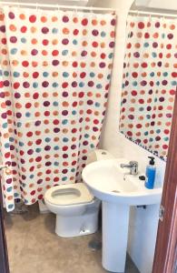 een badkamer met een toilet, een wastafel en een douchegordijn bij Maravilloso alojamiento en pleno centro de Dos Hermanas in Dos Hermanas