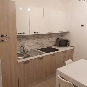 ナポリにあるMERGELLINA APARTMENTの白いキャビネット、シンク、電子レンジ付きのキッチンが備わります。