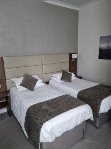 two beds in a hotel room with white sheets and pillows at The Hind Hotel in Wellingborough