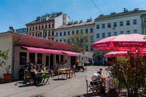 um grupo de pessoas sentadas em mesas com guarda-chuvas rosa em My city apartment - Vienna CityRoom em Viena