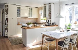 a kitchen with white cabinets and a table and chairs at 2 Bedroom Awesome Home In Frjestaden in Färjestaden