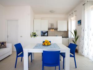 una cucina bianca con tavolo bianco e sedie blu di Marchesana Beach sole mare spiaggia a Terme Vigliatore