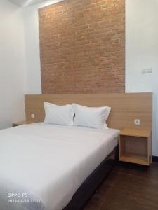 um quarto com uma cama branca e uma parede de tijolos em Villa Aruki Bukittinggi em Bukittinggi