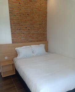 uma cama num quarto com uma parede de tijolos em Villa Aruki Bukittinggi em Bukittinggi