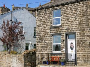 a brick house with a white door and two windows at Canal View Cottage in Keighley