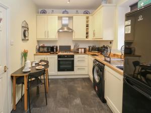 a kitchen with white cabinets and a table and a dishwasher at Canal View Cottage in Keighley