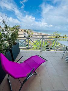 une chaise rose assise sur une terrasse avec vue sur l'océan dans l'établissement Magnifique vue mer - Tout confort, à Pléneuf-Val-André