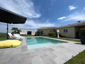 a swimming pool with an umbrella next to a house at Aparté d Eliette Escapade calme et raffinée à 20 minutes de Toulouse in Merville