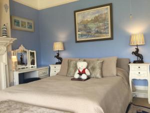 a teddy bear sitting on top of a bed at Arun Sands Rooms in Littlehampton