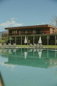 una piscina con sedie e ombrelloni di fronte a un edificio di Solterra Poolhouse 1 a Tesimo