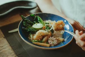 a person holding a bowl of food with a spoon at Solterra Poolhouse 1 in Tesimo