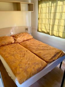 a bed in a room with a yellow blanket on it at Tóparti Camping in Tiszafüred