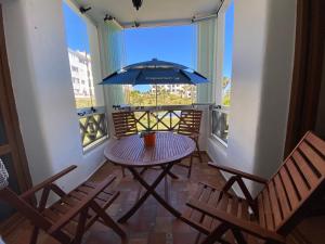 een balkon met een tafel en stoelen en een parasol bij CABO NEGRO - LILAC'S GARDEN - PISCINE - JARDIN - PARKING in Martil