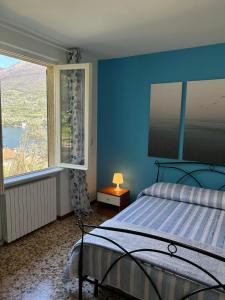 um quarto azul com uma cama e uma grande janela em Sebino Holiday Home em Monte Isola