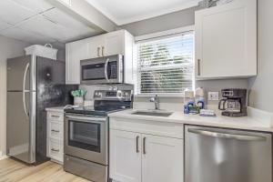 uma cozinha com armários brancos e electrodomésticos de aço inoxidável em Seagrass Sunsets em Bradenton Beach