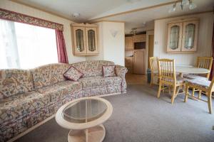 sala de estar con sofá y mesa en 6 Berth Caravan In Hunstanton, Ideal For Seaside Holidays Ref 13004l, en Hunstanton