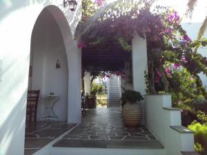 an archway with flowers and a vase on a walk way at Pension Sofia in Parikia