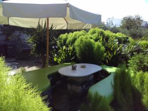 a garden with a table and an umbrella at Pension Sofia in Parikia