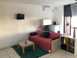 a living room with a red couch and a table at 2024 - grand studio avec piscine et plage à 50 m in San-Nicolao