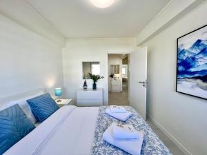 - une chambre avec un grand lit blanc aux accents bleus dans l'établissement Tavira Central by Homing, à Tavira