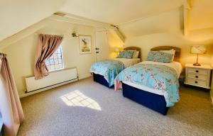 1 dormitorio con 2 camas y ventana en Barn End Cottage, en High Bickington