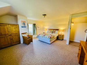 1 dormitorio con cama, silla y vestidor en Barn End Cottage, en High Bickington